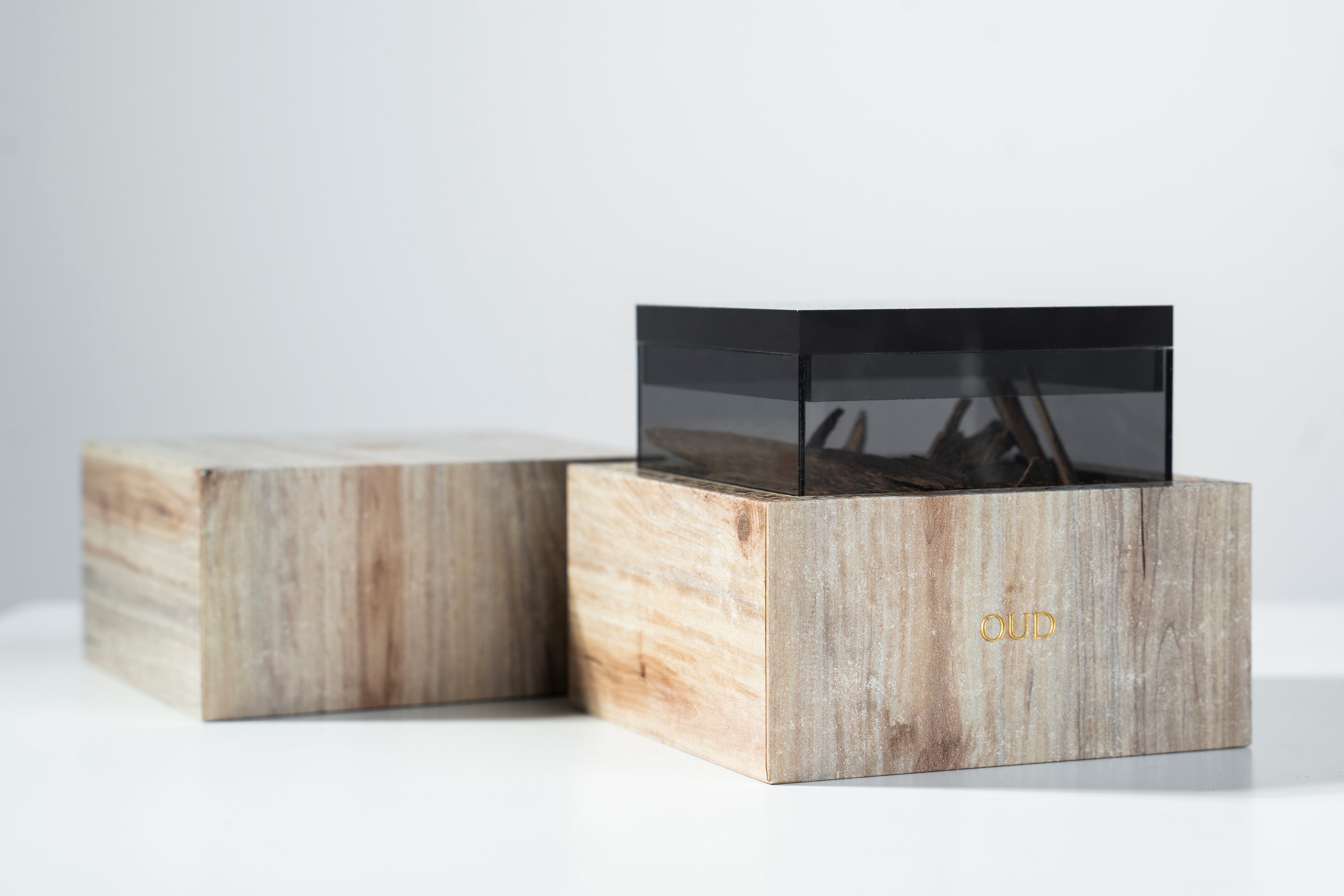 Wooden boxes filled with Oud with a metallic finish on a white background
